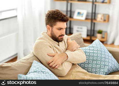 people, health and medicine concept - sad sick man in blanket having fever at home. sad sick man in blanket having fever at home