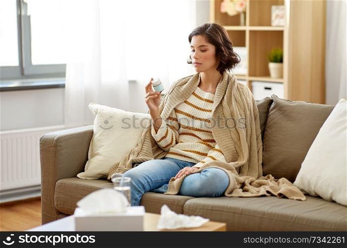 people, health and medicine concept - sad sick woman in blanket with drug at home. sad sick woman in blanket with drug at home