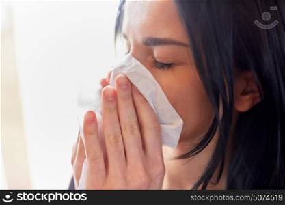 people, health and sadness concept - close up of unhappy woman with paper wipe blowing nose or crying. close up of woman with wipe blowing nose or crying