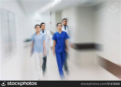 people, health care and medicine concept - group of medics walking along hospital (motion blur effect). group of medics or doctors walking along hospital