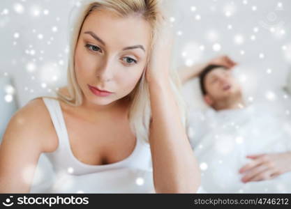 people, health, sleep disorder concept - couple in bed at home, man snoring and young woman suffering from insomnia over snow