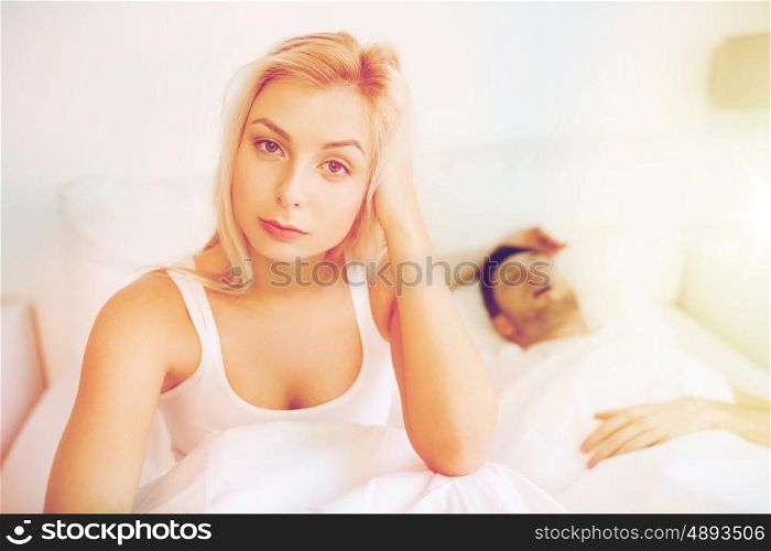 people, health, sleep disorder concept - couple in bed at home, man snoring and young woman suffering from insomnia