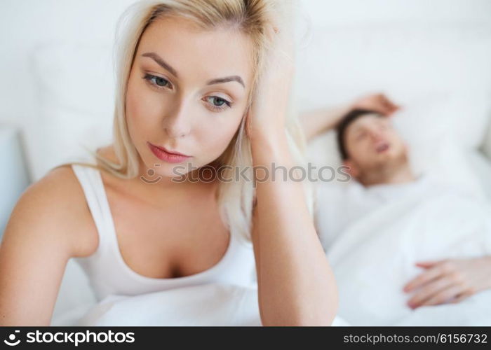 people, health, sleep disorder concept - couple in bed at home, man snoring and young woman suffering from insomnia