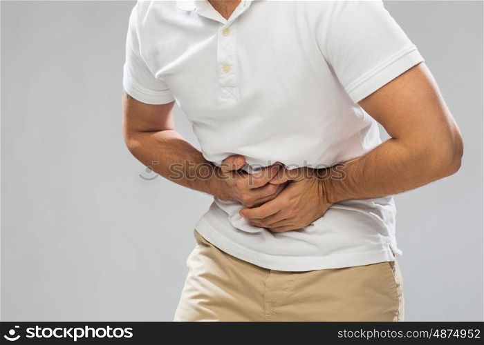 people, healthcare and health problem concept - close up of man suffering from stomach ache over gray background