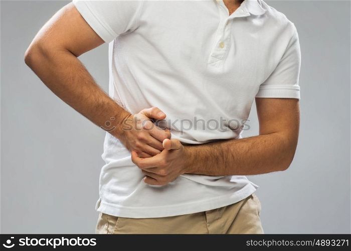 people, healthcare and health problem concept - close up of man suffering from stomach ache over gray background