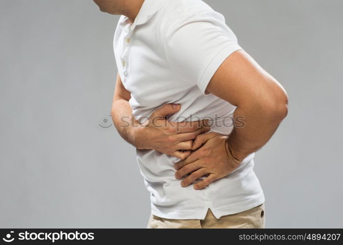 people, healthcare and health problem concept - close up of man suffering from pain in side over gray background