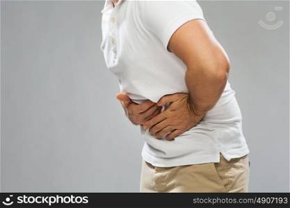 people, healthcare and health problem concept - close up of man suffering from stomach ache over gray background. close up of man suffering from stomach ache