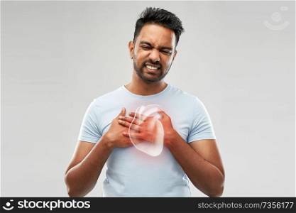 people, healthcare and health problem concept - unhappy man having heart attack or heartache over grey background. unhappy man having heart attack or heartache