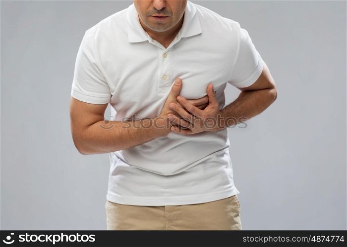 people, healthcare and problem concept - close up of man suffering from heart ache over gray background