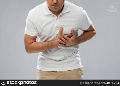 people, healthcare and problem concept - close up of man suffering from heart ache over gray background