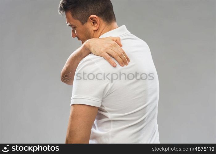 people, healthcare and problem concept - close up of man suffering from pain in upper back over gray background