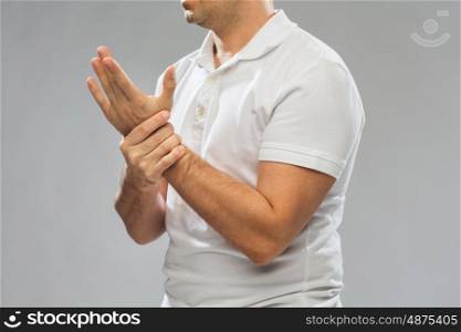 people, healthcare and problem concept - close up of man suffering from pain in hand over gray background