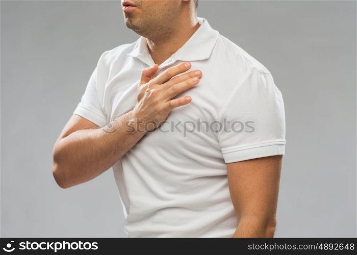 people, healthcare and problem concept - close up of man suffering from heart ache or chest pain over gray background