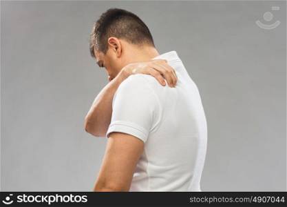 people, healthcare and problem concept - close up of man suffering from pain in upper back over gray background. close up of man suffering from backache