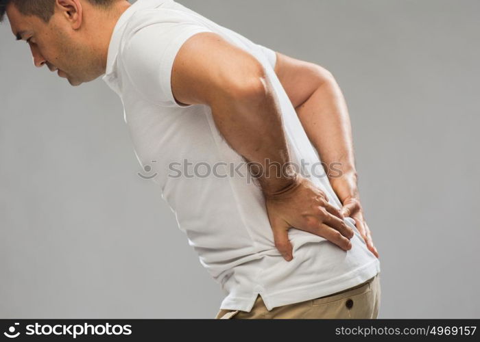 people, healthcare and problem concept - close up of man suffering from pain in back or reins over gray background. close up of man suffering from backache