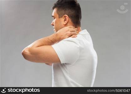 people, healthcare and problem concept - close up of man suffering from neck pain over gray background. close up of man suffering from neck pain