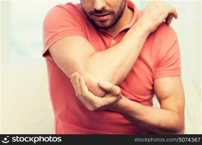 people, healthcare and problem concept - close up of man suffering from pain in hand or elbow at home. close up of man with injured hand at home