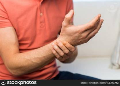 people, healthcare and problem concept - close up of man suffering from pain in hand oe wrist at home
