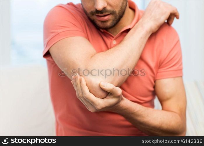 people, healthcare and problem concept - close up of man suffering from pain in hand or elbow at home
