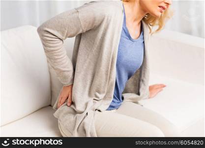 people, healthcare and problem concept - close up of unhappy woman suffering from pain in back or reins at home