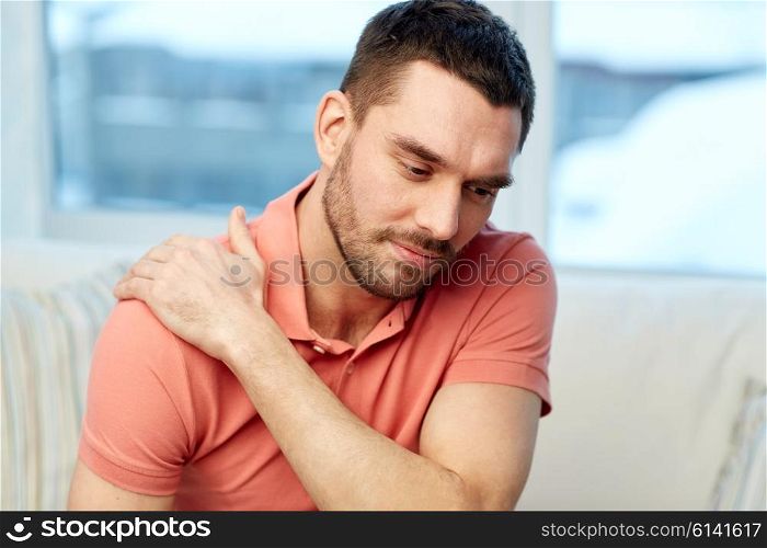 people, healthcare and problem concept - unhappy man suffering from neck or shoulder pain at home