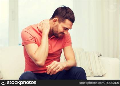 people, healthcare and problem concept - unhappy man suffering from neck pain at home. unhappy man suffering from neck pain at home