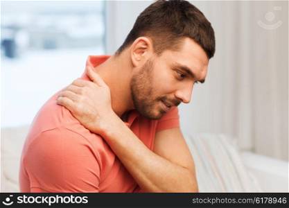 people, healthcare and problem concept - unhappy man suffering from neck pain at home
