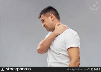 people, healthcare and problem concept - unhappy man suffering from neck pain over gray background