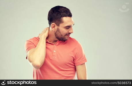 people, healthcare and problem concept - unhappy man suffering from neck pain over gray background. unhappy man suffering from neck pain