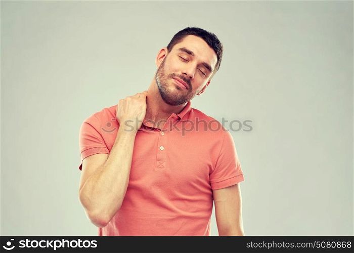 people, healthcare and problem concept - unhappy man suffering from neck pain over gray background. unhappy man suffering from neck pain
