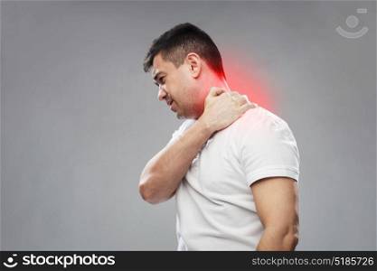 people, healthcare and problem concept - unhappy man suffering from neck pain over gray background. unhappy man suffering from neck pain