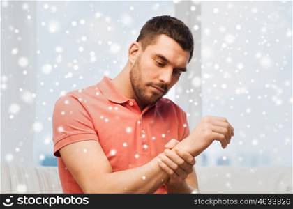 people, healthcare and problem concept - unhappy man suffering from pain in hand at home over snow