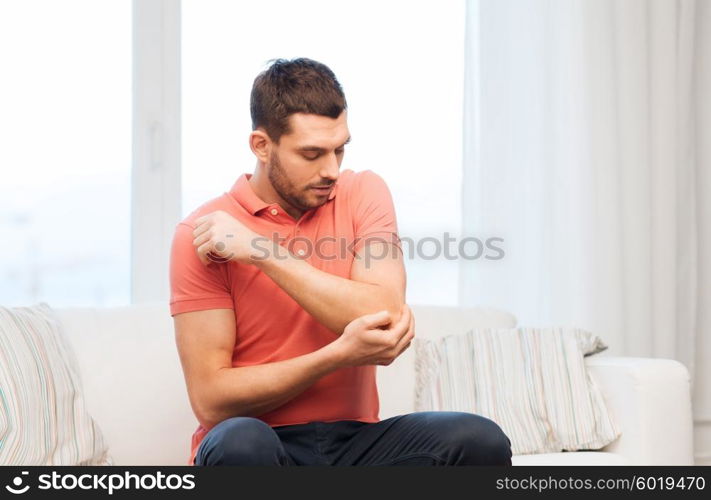 people, healthcare and problem concept - unhappy man suffering from pain in hand at home