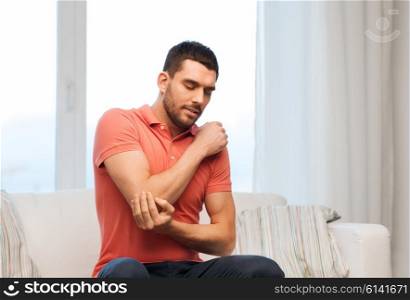 people, healthcare and problem concept - unhappy man suffering from pain in hand at home