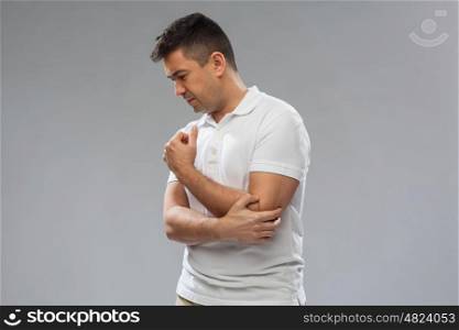 people, healthcare and problem concept - unhappy man suffering from pain in hand over gray background