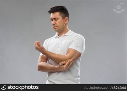 people, healthcare and problem concept - unhappy man suffering from pain in hand over gray background