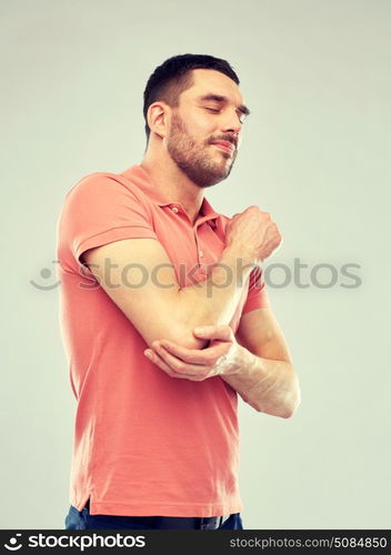 people, healthcare and problem concept - unhappy man suffering from pain in hand over gray background. unhappy man suffering from pain in hand. unhappy man suffering from pain in hand