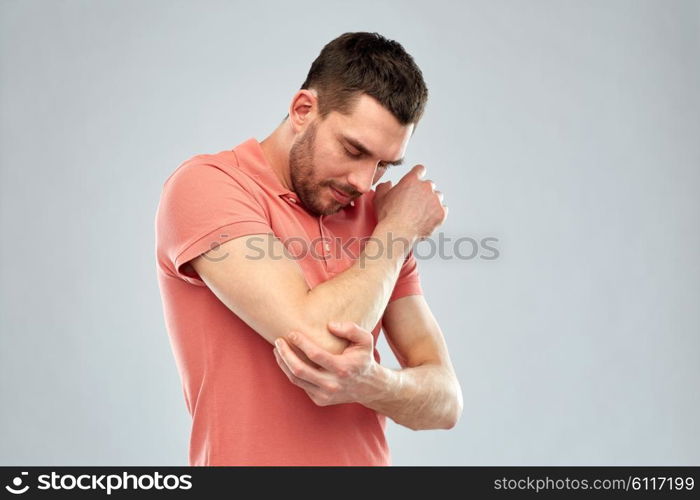 people, healthcare and problem concept - unhappy man suffering from pain in hand over gray background