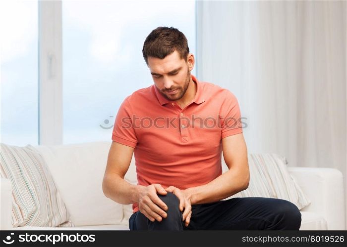 people, healthcare and problem concept - unhappy man suffering from pain in leg at home