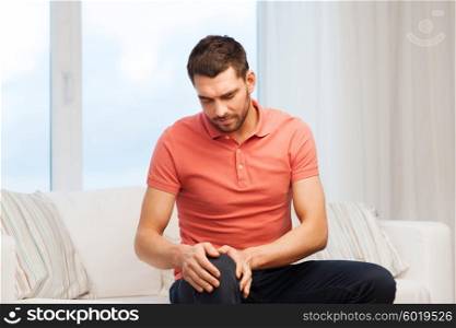 people, healthcare and problem concept - unhappy man suffering from pain in leg at home