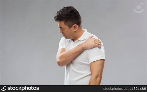 people, healthcare and problem concept - unhappy man suffering from pain in shoulder over gray background