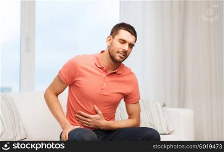 people, healthcare and problem concept - unhappy man suffering from stomach ache at home