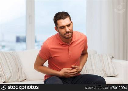 people, healthcare and problem concept - unhappy man suffering from stomach ache at home