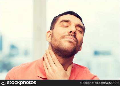 people, healthcare and problem concept - unhappy man touching her neck and suffering from throat pain at home. unhappy man suffering from throat pain at home