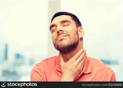 people, healthcare and problem concept - unhappy man touching her neck and suffering from throat pain at home. unhappy man suffering from throat pain at home