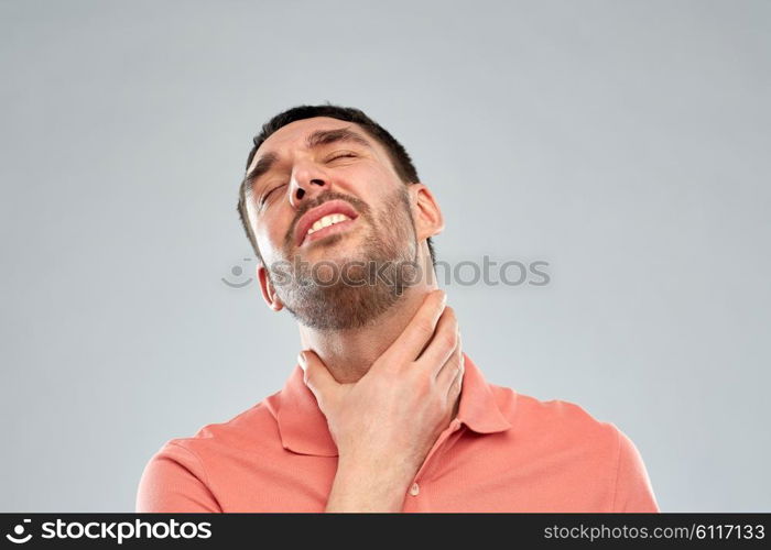 people, healthcare and problem concept - unhappy man touching his neck and suffering from throat pain over gray background