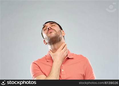 people, healthcare and problem concept - unhappy man touching his neck and suffering from throat pain over gray background