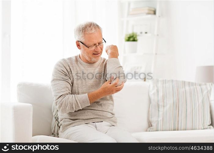 people, healthcare and problem concept - unhappy senior man suffering from elbow pain at home