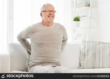 people, healthcare and problem concept - unhappy senior man suffering from pain in back or reins at home