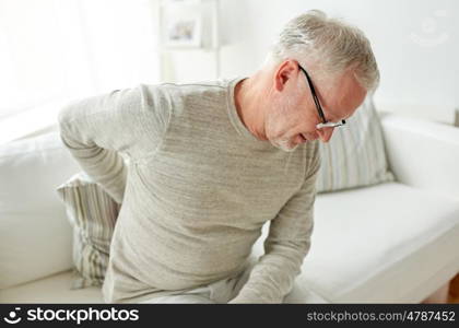 people, healthcare and problem concept - unhappy senior man suffering from pain in back or reins at home